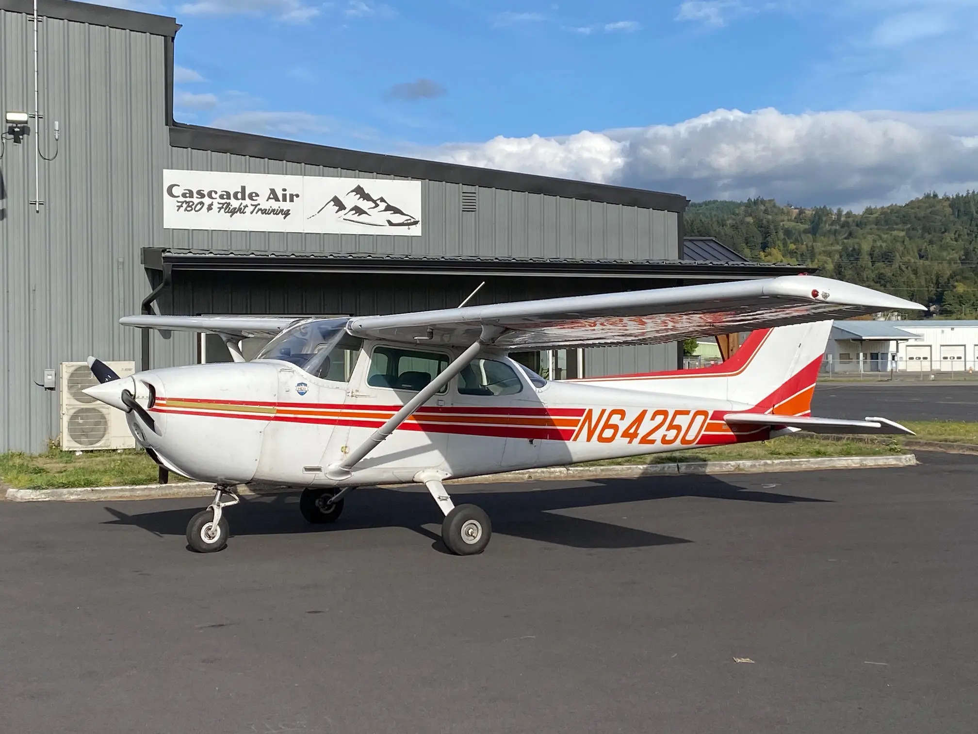 Cessna 172M N64250 parked in front of the Cascade Air FBO and Flight Training hangar at KKLS.
